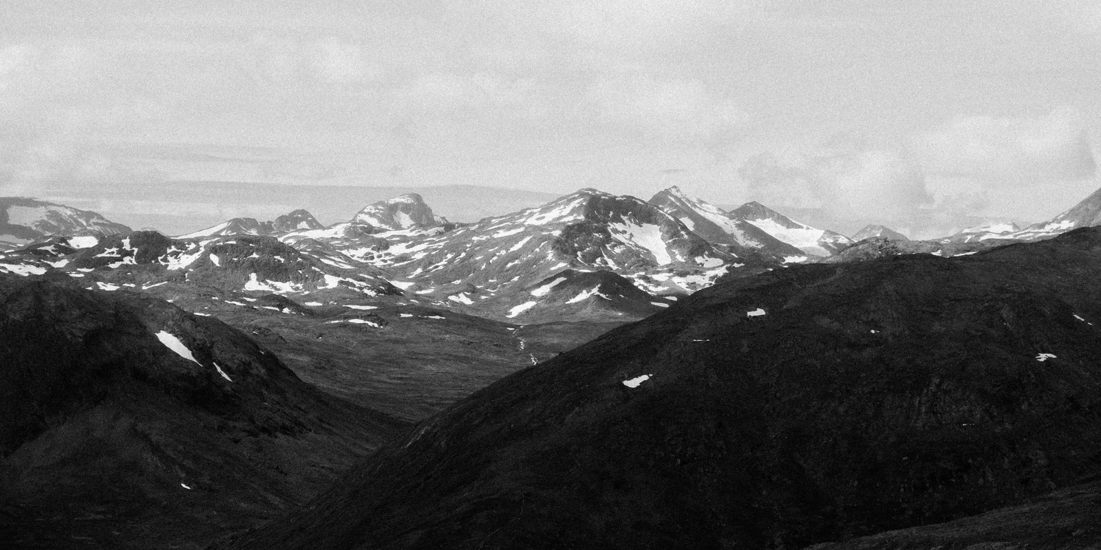 A black and white panorama of mountain ridges with patches of snow