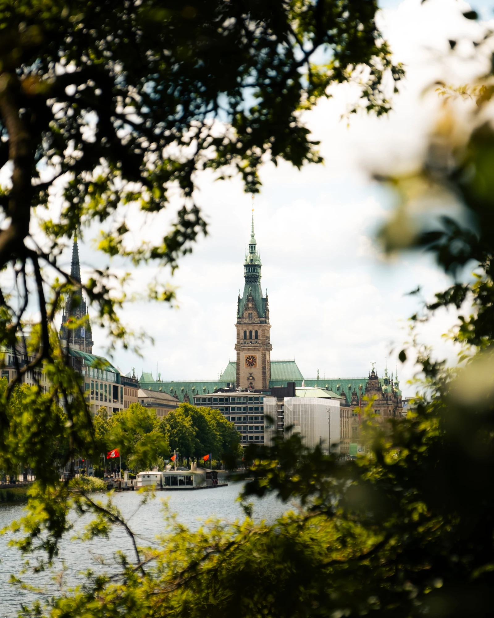 A slender clock tower framed by trees across an open square