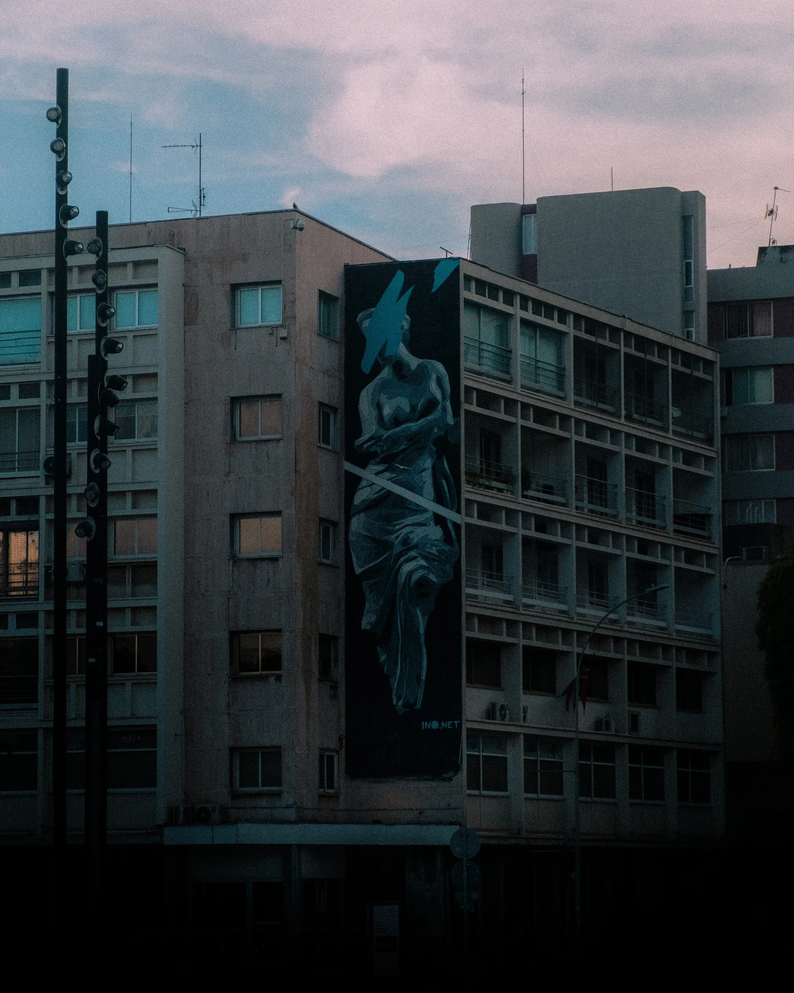 A large mural on a concrete building beneath a pastel evening sky