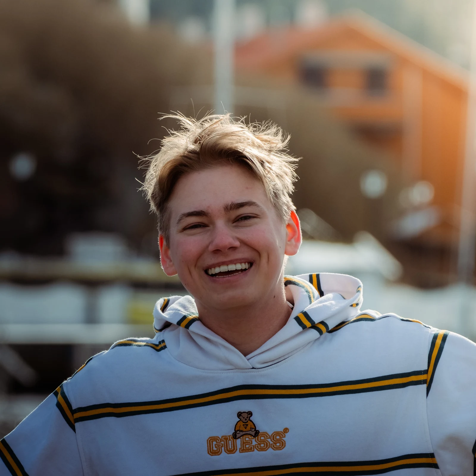 A smiling person in a striped shirt photographed in warm backlight