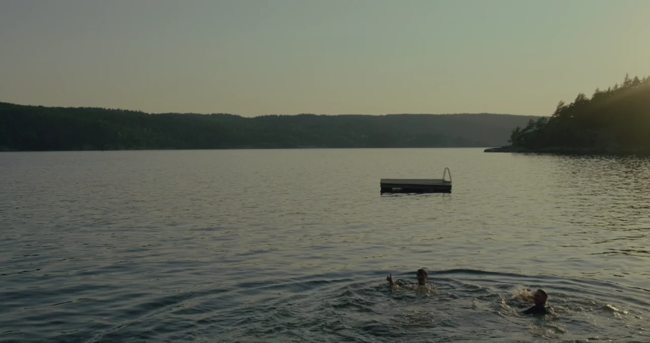 Swimming in a lake beside a floating platform and forested hills